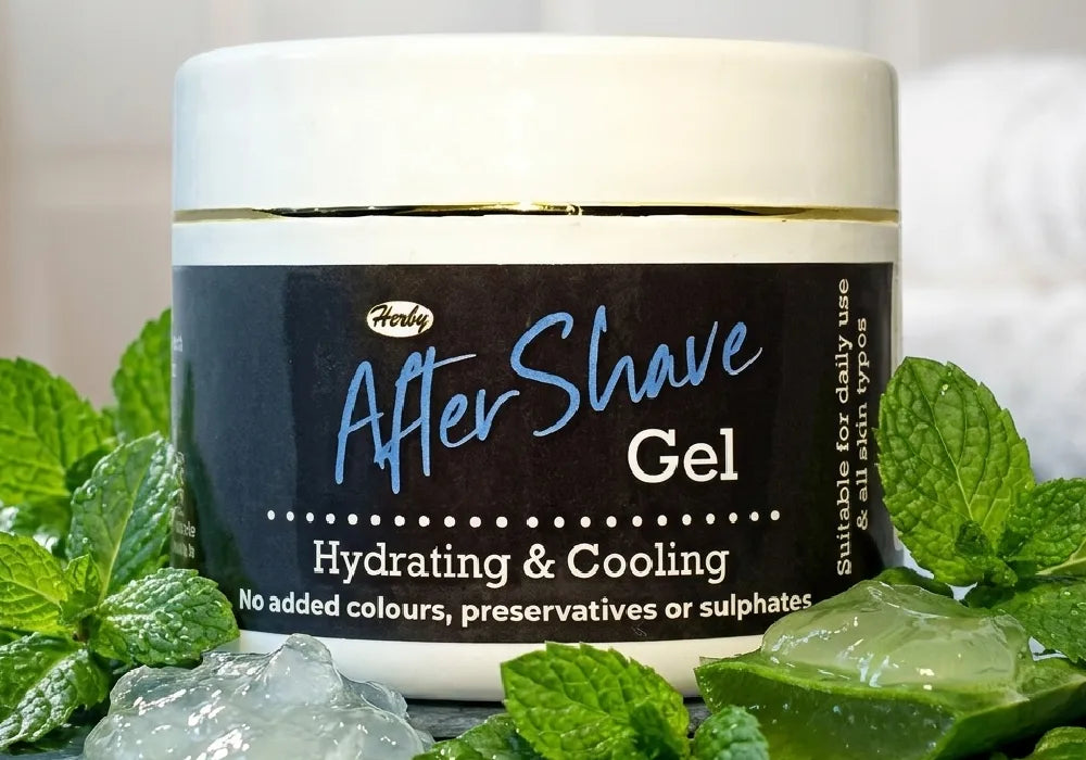  A bottle of cooling after shave gel for men surrounded by fresh mint leaves and raw aloe vera gel.